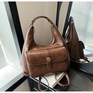 Dettaglio della texture in pelle PU marrone e della fibbia in metallo retrò della borsa hobo