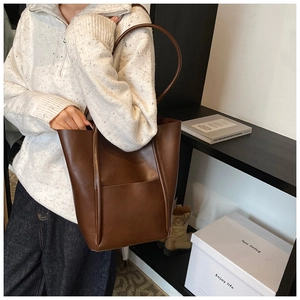 Close-up of brown matte faux leather tote bag with exterior pocket and slim shoulder strap