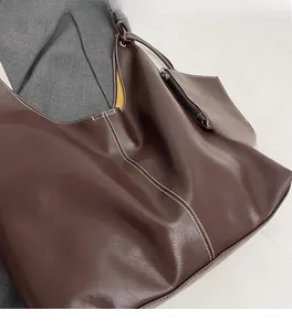 Détail du sac cabas marron foncé avec surpiqûres blanches et mini pochette zippée