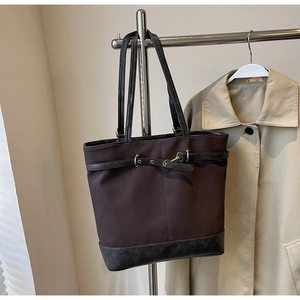 Detail of dark brown tote bag showing matte texture and golden ring hardware