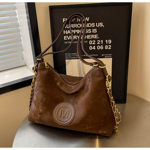 Gros plan d'un sac cabas vintage marron foncé avec logo M et double bandoulière