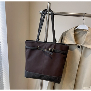 Detail of vintage brown tote bag with gold metal equestrian buckle and black trim