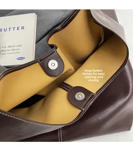 Gros plan sur le fermoir magnétique et les surpiqûres blanches d'un sac cabas marron