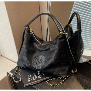 Détail du sac cabas en cuir rétro noir avec logo M gaufré et chaîne dorée élégante