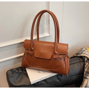 Detailed close-up of brown vintage leather bag featuring gold PAN TOR logo and buckle