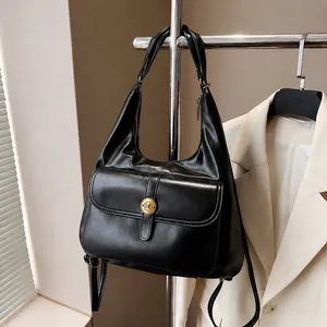 Dettaglio della borsa hobo in pelle nera opaca con fibbia tonda dorata e tasca frontale