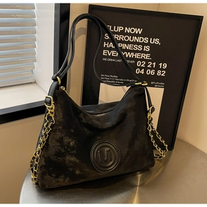Détail du cabas vintage noir avec logo M embossé et bandoulière en chaîne dorée chic