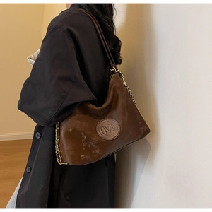 Détail du sac cabas marron vintage avec logo M embossé et chaîne dorée chic