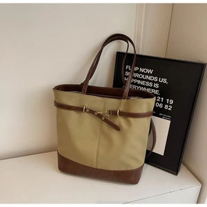 Detail of khaki tote bag with dark brown leather trim and golden horsebit buckle hardware