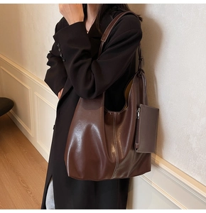 Detail of dark brown leather hobo bag with contrast white stitching and small pouch