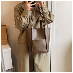 Close-up of a brown vintage leather bucket bag styled with a khaki trench coat