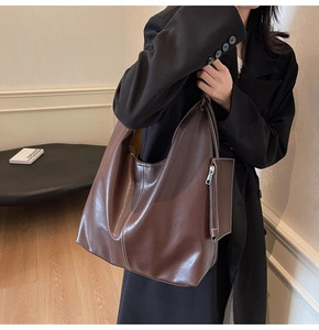 Détail d'un grand sac cabas marron avec coutures blanches et pochette zippée assortie