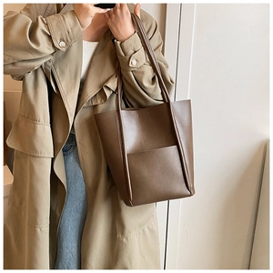 Deep brown matte leather tote bag detail with large front pocket and slim shoulder straps
