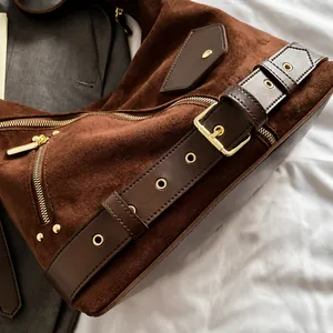 Macro view of brown suede texture with gold metal buckles and zipper hardware details