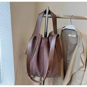 Detail of dark brown vintage suede bucket bag with smooth leather strap and texture