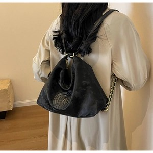 Détail du sac à dos noir en cuir mat avec logo M en relief et chaîne dorée décorative