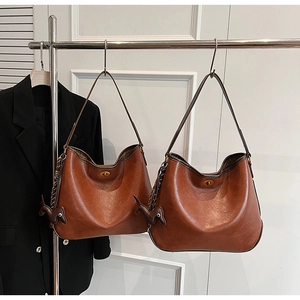 Close-up of vintage brown leather tote bag with metal twist lock and horse charm
