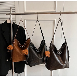 Sacs hobo rétro marron et noir avec breloques d'ours en peluche suspendus sur un rack