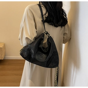 Détail du cabas noir avec emblème M en métal et bandoulière en cuir et chaîne