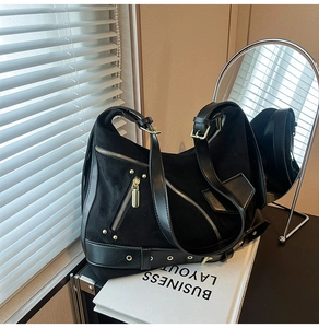Detail of black motorcycle style hobo bag featuring gold zippers and buckle accents
