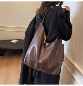 Dettaglio della borsa tote marrone scuro con cuciture a contrasto e fodera gialla
