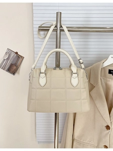 Beige quilted leather Boston bag with crossbody strap shown in a lifestyle setting