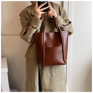 Brown leather bucket tote bag with rectangular front pocket and slim shoulder straps