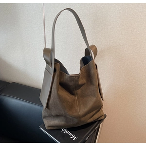 Detail of dark brown matte suede tote bag with unique side leather decorative patches