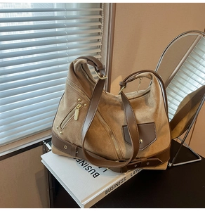 Close-up of khaki suede tote bag with brown leather trim and golden metal zippers