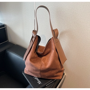 Detail of premium brown suede hobo bag with contrast leather trim on a black chair