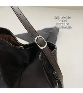 Détail de la boucle argentée réglable et de la bandoulière en cuir du sac seau