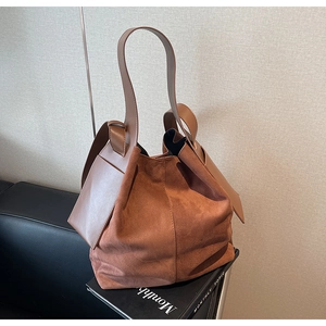 Detailed texture of brown suede bucket bag with leather strap on vintage background