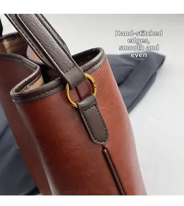 Detail einer braunen Ledertasche mit handgenähten Kanten und goldener Ringbeschlag