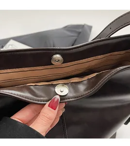 Détail de la boucle magnétique et de la doublure rayée sur le cabas en cuir mat vintage