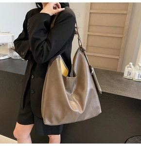 Detail of coffee brown leather hobo bag with contrast white stitching and yellow lining