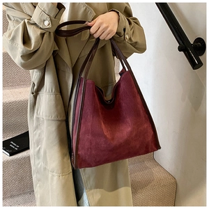 Detail der burgunderroten Wildledertasche mit braunen Ledergriffen und Nähten am Modell