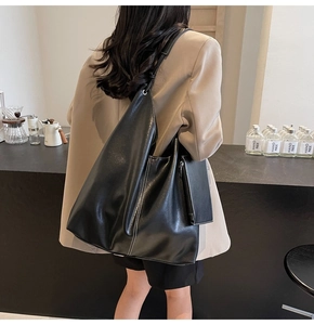 Détail d'un sac cabas en cuir noir avec une petite pochette zippée dans un café