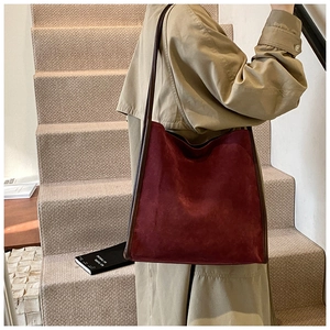 Burgunderrote Shopper-Tasche aus Wildleder mit Lederriemen von einem Model getragen