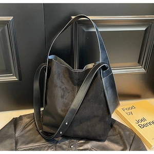 Detail of black suede bucket bag with adjustable strap and textured leather finish