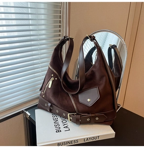 Detail view of brown suede hobo bag with gold metal zippers and decorative leather straps