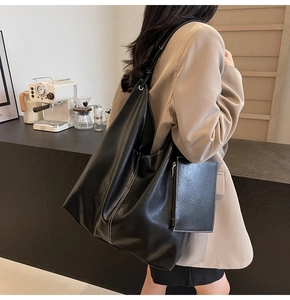 Detail of black tote bag featuring white contrast stitching and a matching small pouch