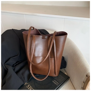 Close-up of vintage brown leather tote bag on beige chair with modern artistic backdrop