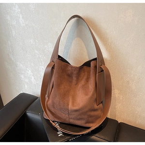 Detail of caramel brown suede tote bag with smooth leather trim and side strap design