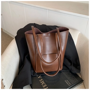 Detail of a dark brown leather tote bag with a front pocket and long shoulder straps
