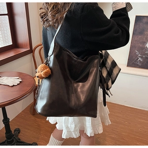 Gros plan d'un grand sac cabas vintage marron café avec un pendentif chien en peluche mignon