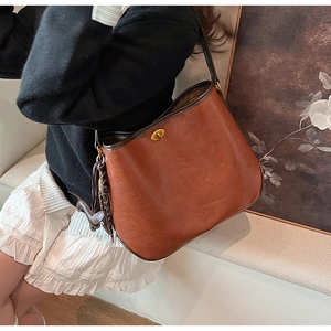 Detail of vintage brown leather hobo bag featuring a gold twist lock and a cute animal charm