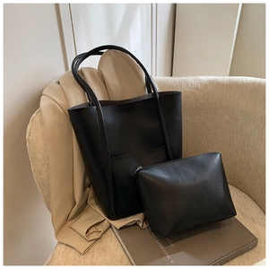 Macro shot of minimalist black leather bucket bag set with matching small zipper pouch