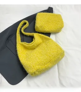 Detailed view of yellow plush tote bag and matching pouch on a grey suit background