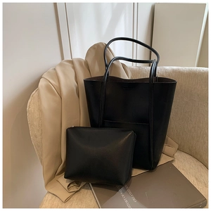 Detail of black pebbled leather tote set with matching interior pouch on a stylish backdrop