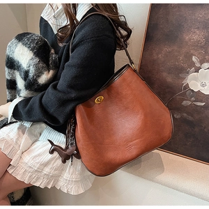 Detail of vintage brown leather bucket bag with gold clasp and small horse charm